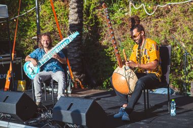 Yoav Fekete (YoYo Sitar) on a festival stage playing sitar beside kora player Tomer Yehieli