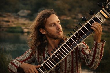 Yoav Fekete (YoYo Sitar) with his sitar beside a river among the rocks of Hampi, India
